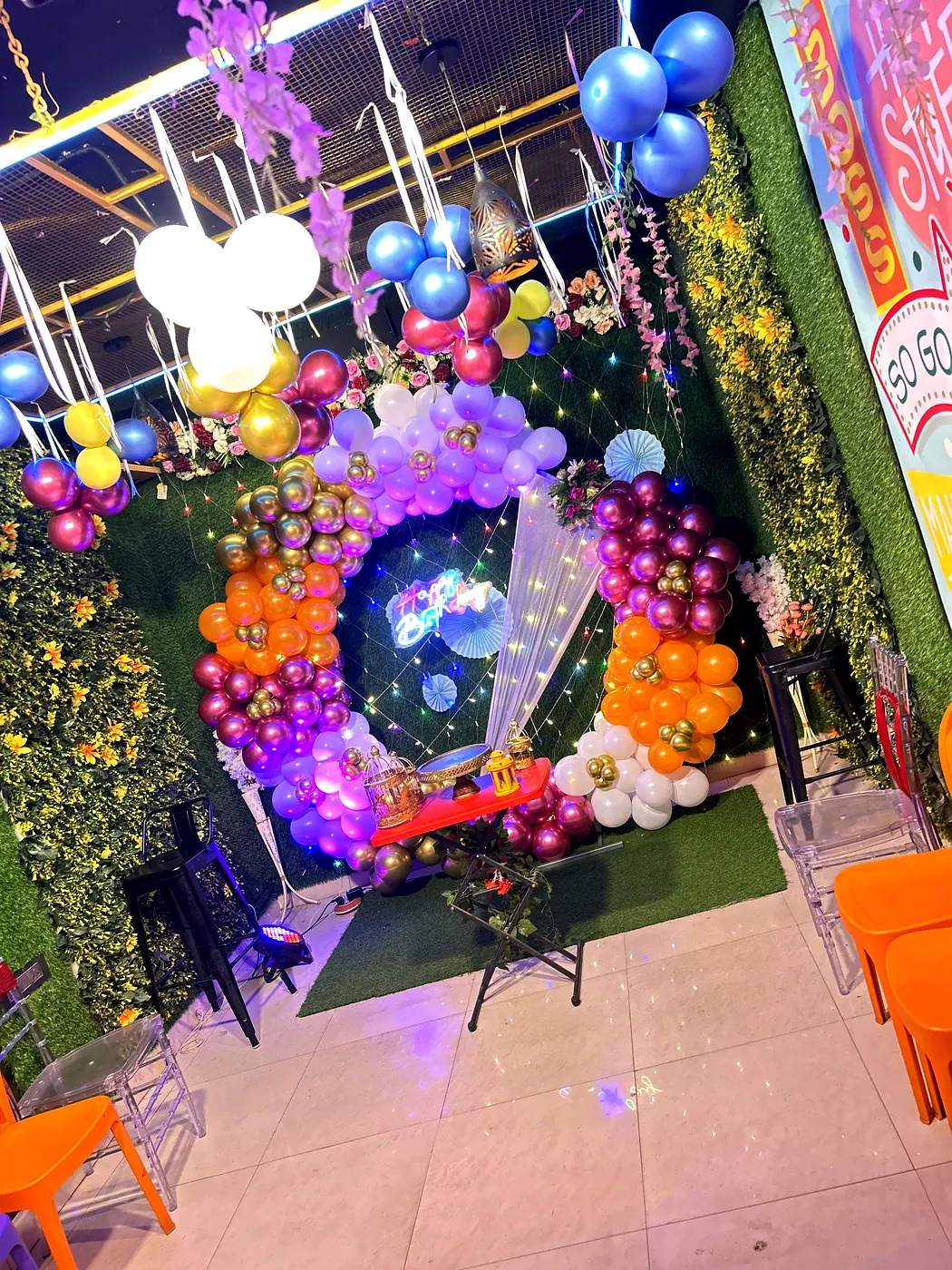Gold orange and maroon balloon arch with Happy Birthday neon sign at JD Party Box