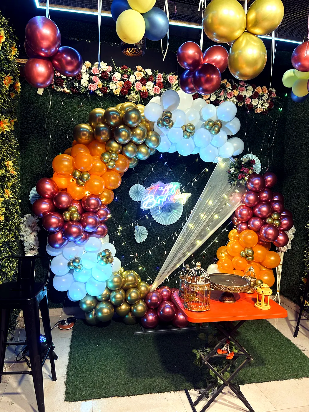 Gold white and maroon balloon arch backdrop with birdcage props at JD Party Box